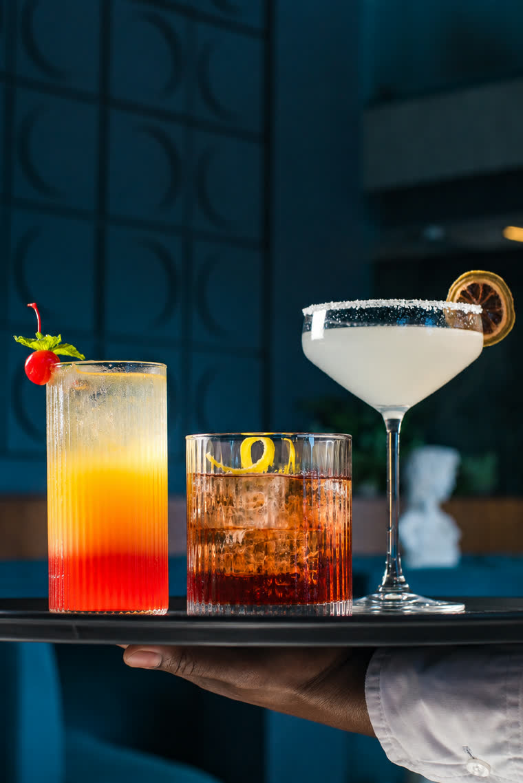 Three signature cocktails served on a tray