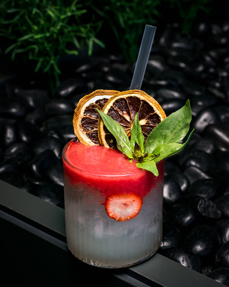 Cocktail with basil, strawberry and dried citrus on black stones
