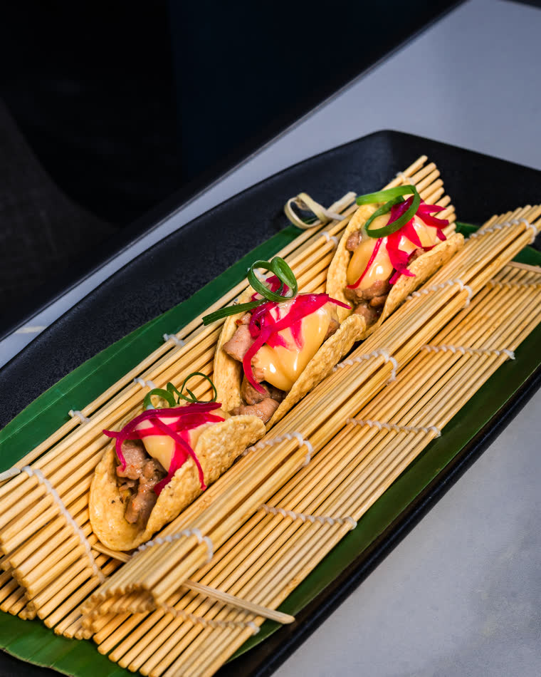 Tacos with pickled onion and spring onion on a bamboo mat